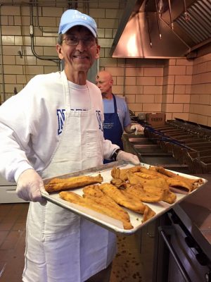 A parishioner holding a tray of breaded fish.